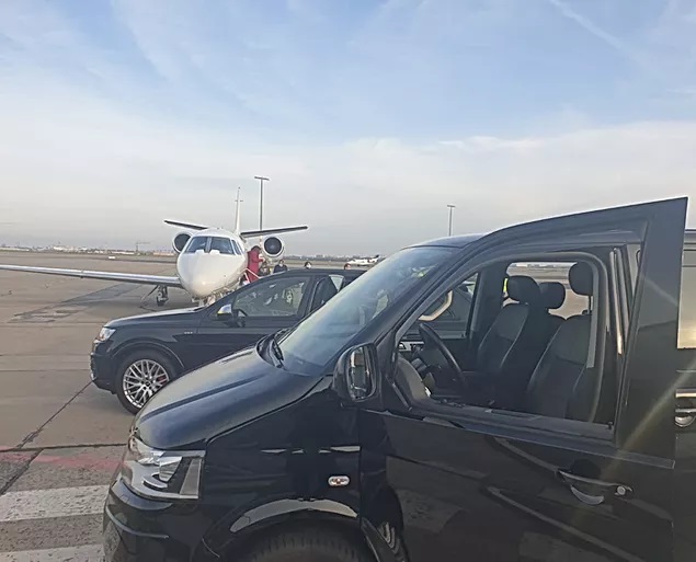 Fahrzeuge des Fahrservice auf dem Flughafenvorfeld neben einem Privatjet